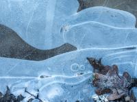 Milchige, geschwungene und runde Strukturen im klaren Eis